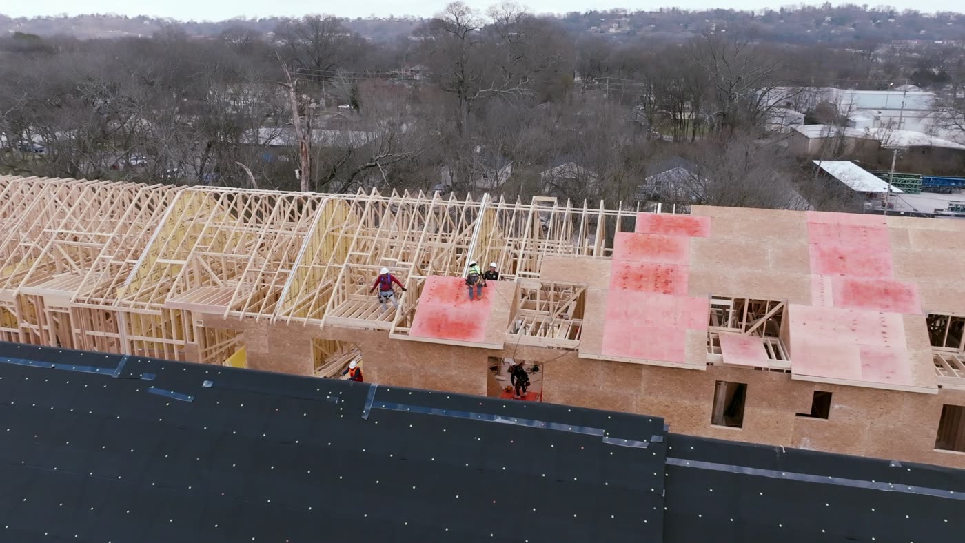 Roofing crew working on a roof deck with underlayment